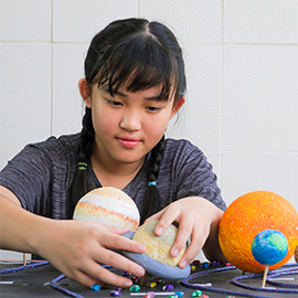 teenage girl building 3-dimensional solar system model