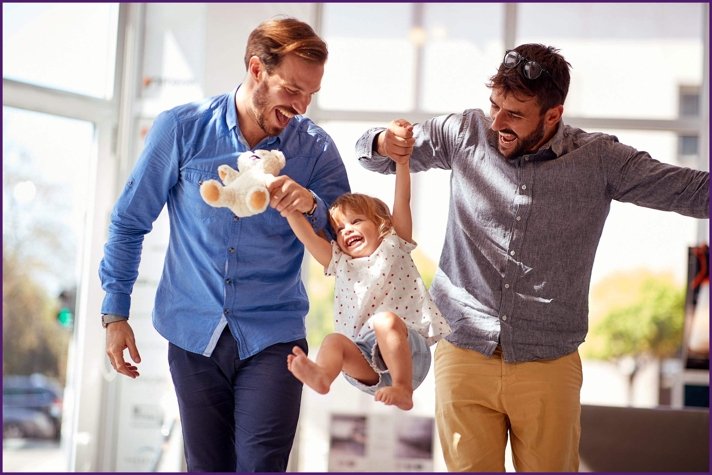two fathers holding up their young child