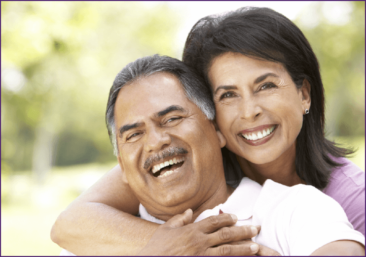 Happy retired couple hugging outside on a sunny day